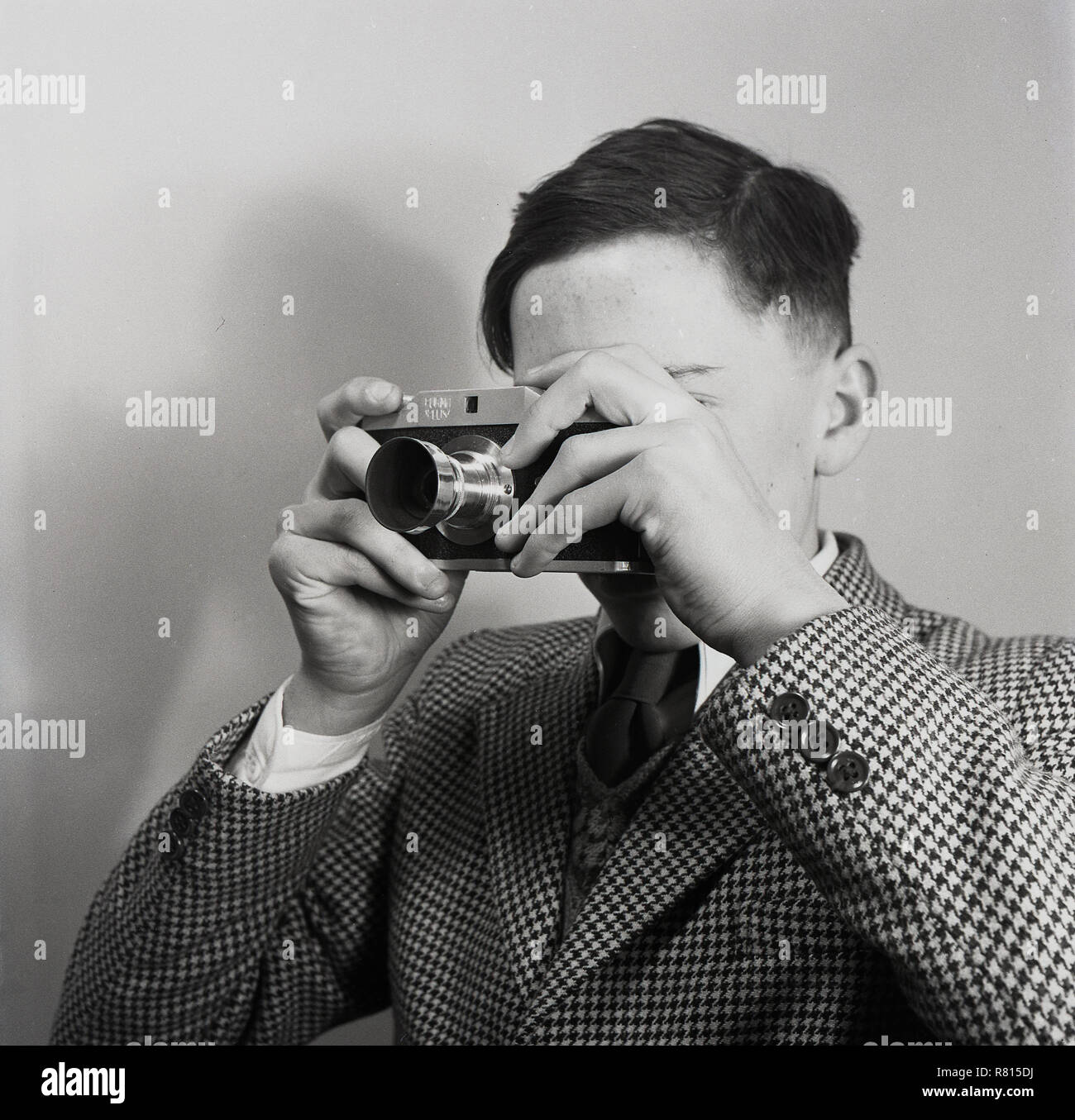 Années 1950, la photographie du film, historique, adolescent garçon portant une veste et cravate smart vérifier en utilisant une caméra de l'époque avec un pare-soleil, England, UK. La photographie est un passe-temps populaire dans les années 50 et 60. Banque D'Images