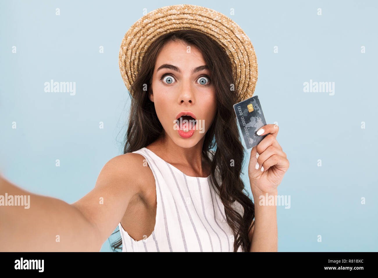 Image de belle jeune femme excité choc isolé sur fond bleu mur font un appareil photo par selfies holding credit card. Banque D'Images