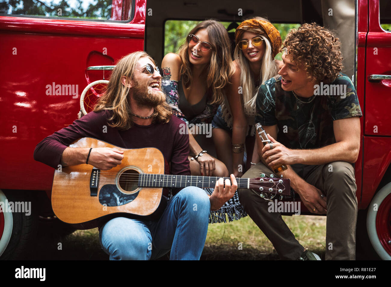 Groupe de jeunes hippies, hommes et femmes de rire et jouer la guitare  vintage près de la nature en minibus Photo Stock - Alamy