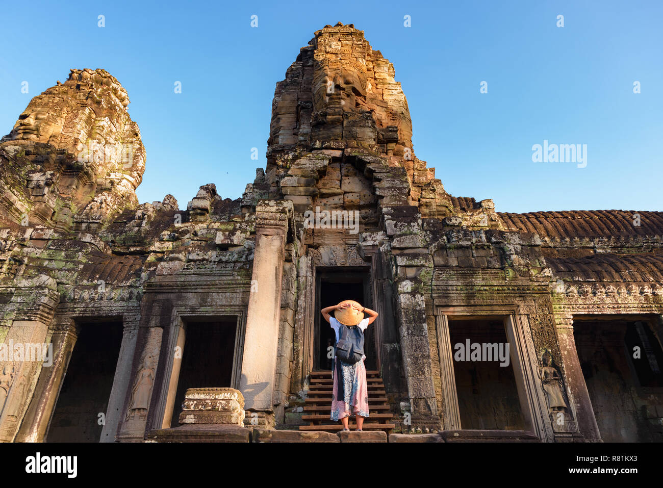 Femme au temple Bayon à la pierre à visages, Angkor Thom, lumière du matin, ciel bleu clair. Concept la méditation, célèbre destination de voyage, Banque D'Images