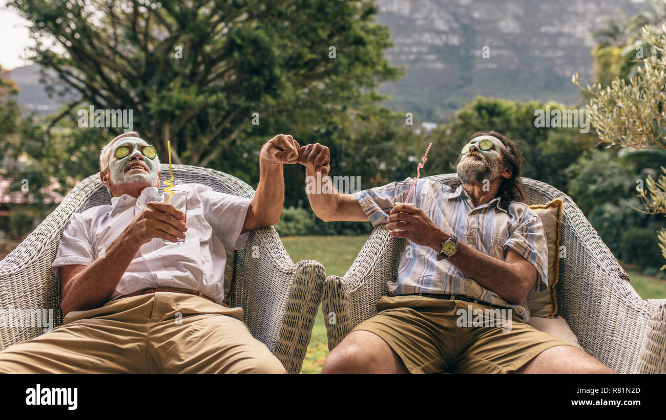 Les hommes avec de l'argile masque du visage sur la face donnant à chaque autre fist bump. Les hommes âgés bénéficiant d'un soin spa du visage. Banque D'Images