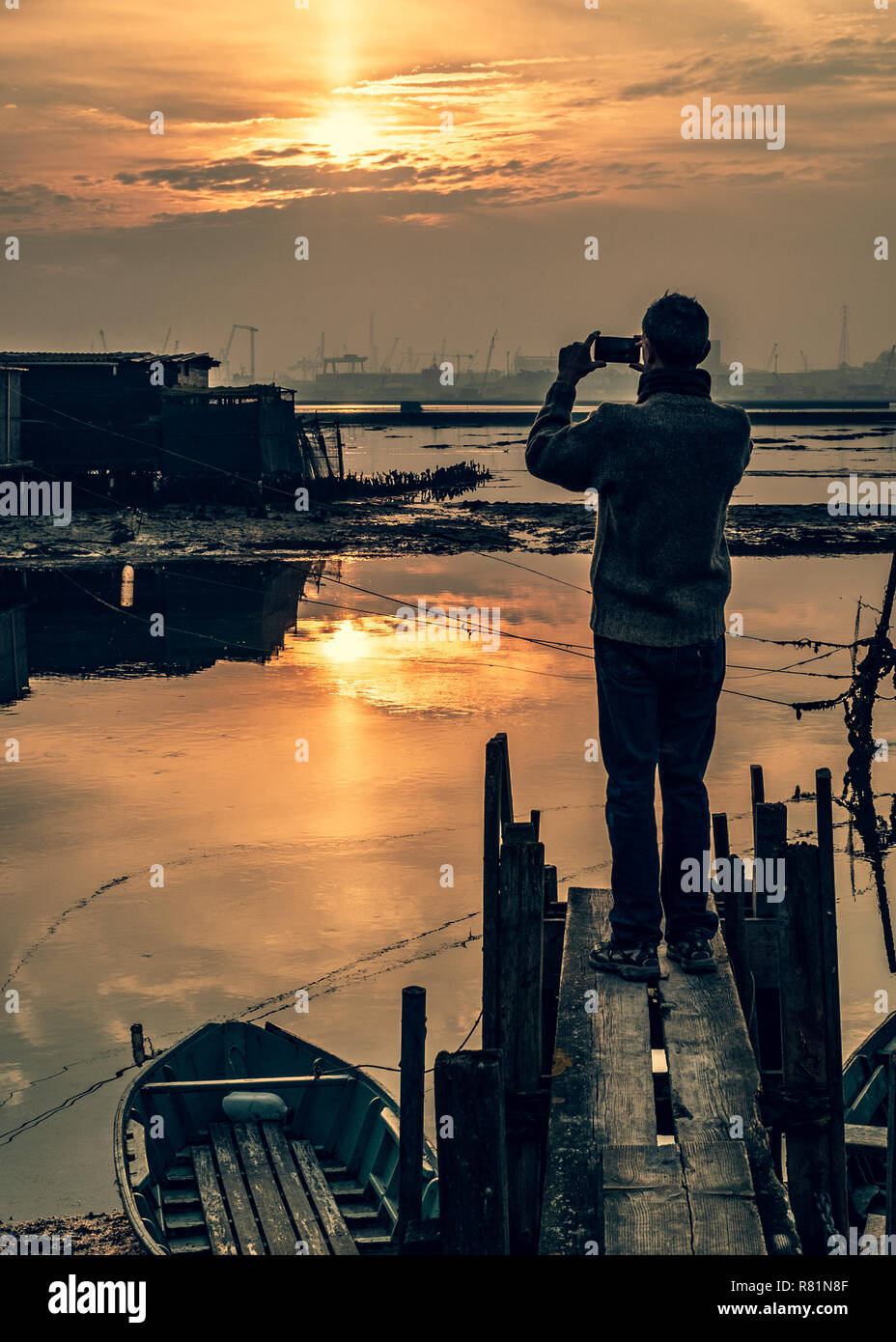 L'homme est en photo avec un smartphone au coucher du soleil. Marina di Ravenna Ravenna Province, lagune, Emilia Romagna, Italie. Banque D'Images