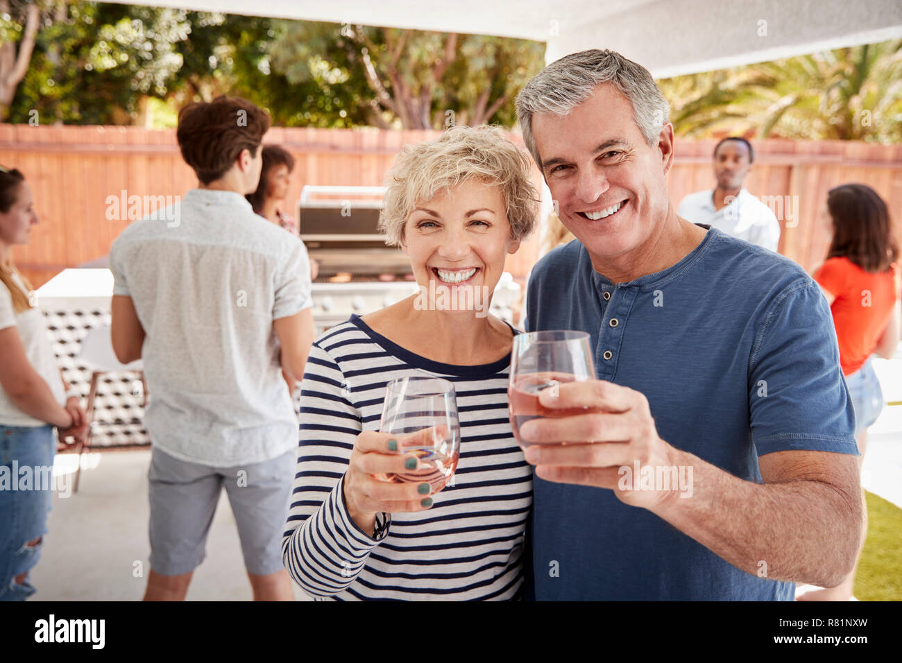 Senior couple lors d'une arrière cour raising glasses à l'appareil photo Banque D'Images