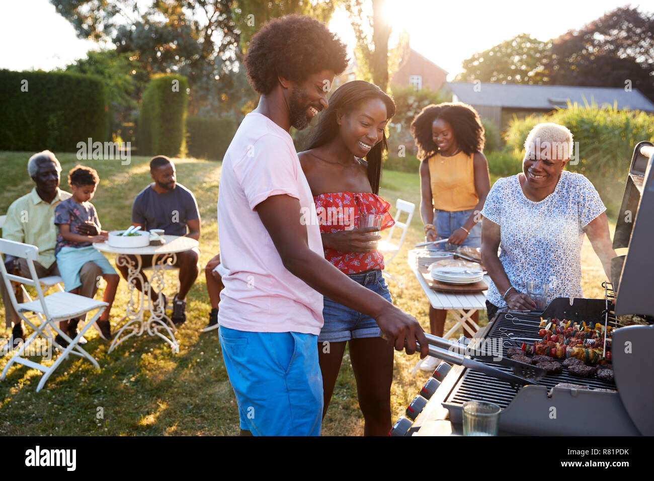 La cuisson à un couple black multi generation family barbecue Banque D'Images