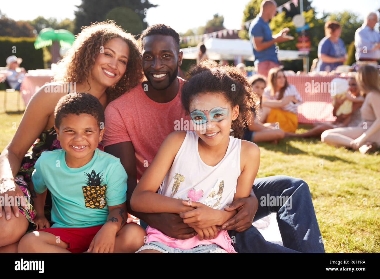 Portrait de famille avec des enfants assis sur un tapis au jardin d'été Fete Banque D'Images