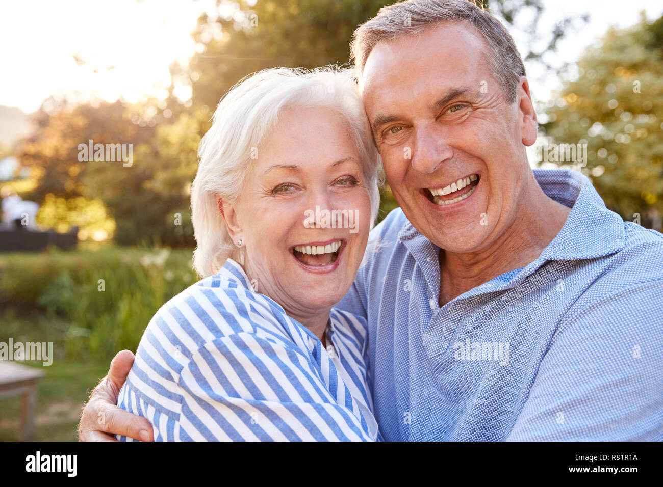 Portrait de Senior Couple Hugging Outdoors in Summer Park contre Sun Torchage Banque D'Images