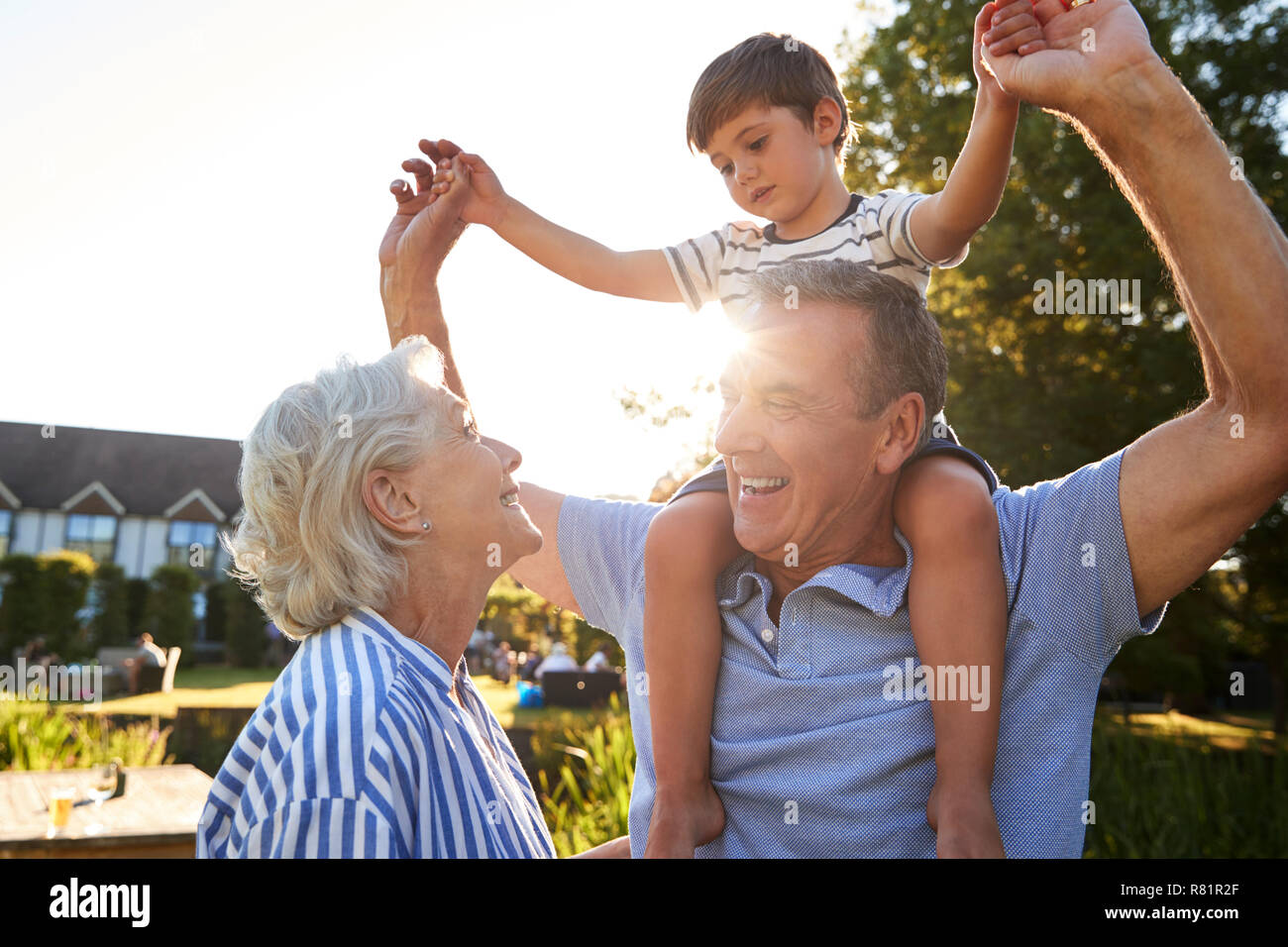 Les grands-parents petit-fils donnant tour sur les épaules en parc d'été contre le soleil à la torche Banque D'Images