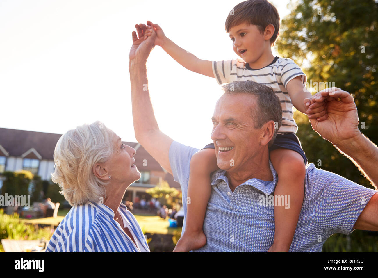 Les grands-parents petit-fils donnant tour sur les épaules en parc d'été contre le soleil à la torche Banque D'Images