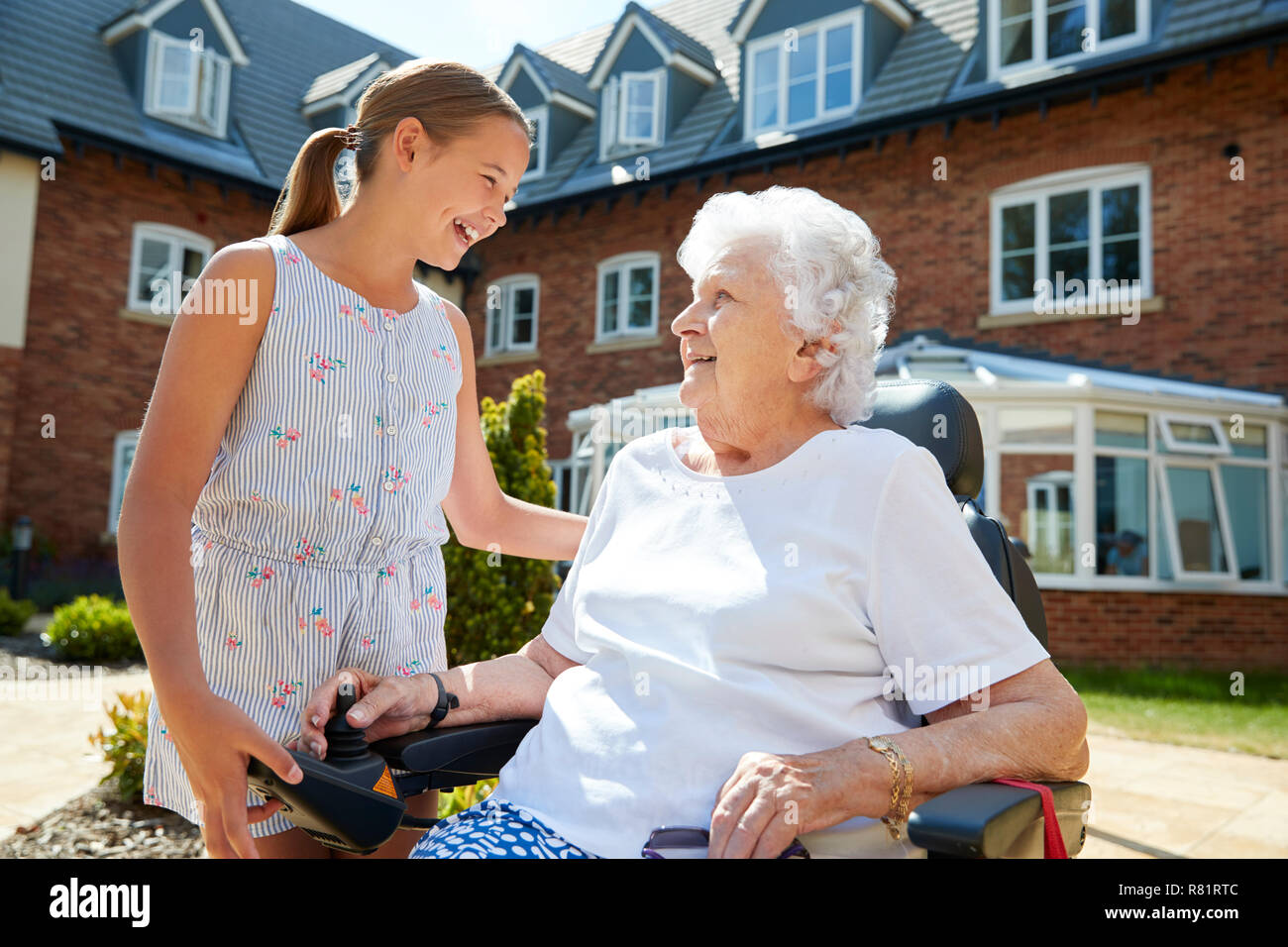 Petite-fille de visiter grand-mère assis en fauteuil roulant motorisé en maison de retraite Banque D'Images