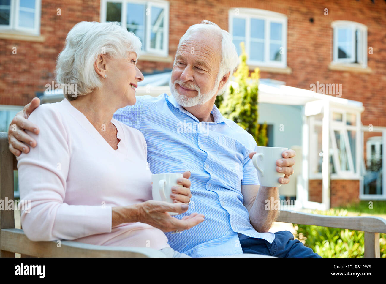 Couple de retraités assis sur un banc avec boisson chaude en résidence-services Banque D'Images