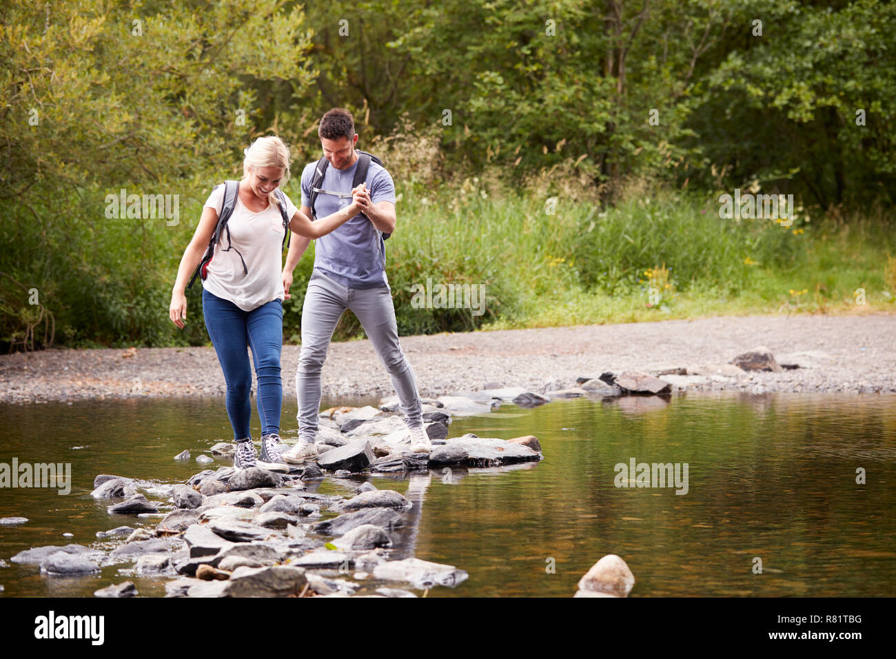 Couple Crossing River alors que la randonnée au Royaume-Uni Lake District Banque D'Images