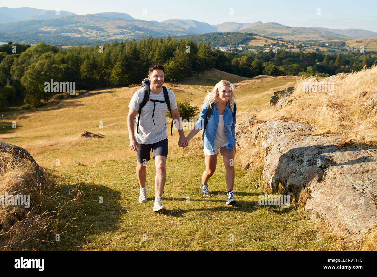 Couple Climbing Hill sur la randonnée à travers la campagne de Lake District UK Ensemble Banque D'Images