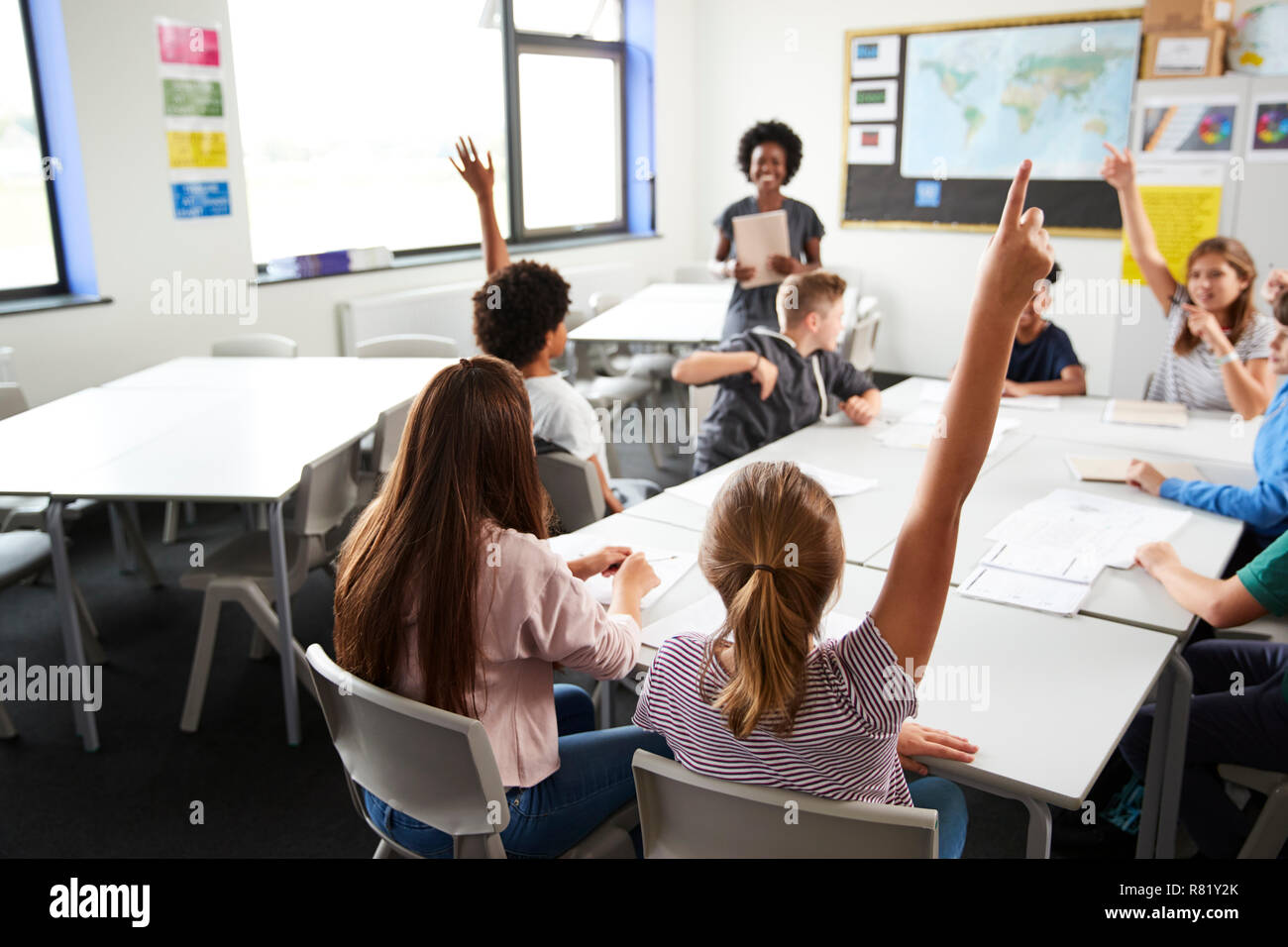 High School Students Raising Hands pour répondre à question posée par Teacher In Classroom Banque D'Images