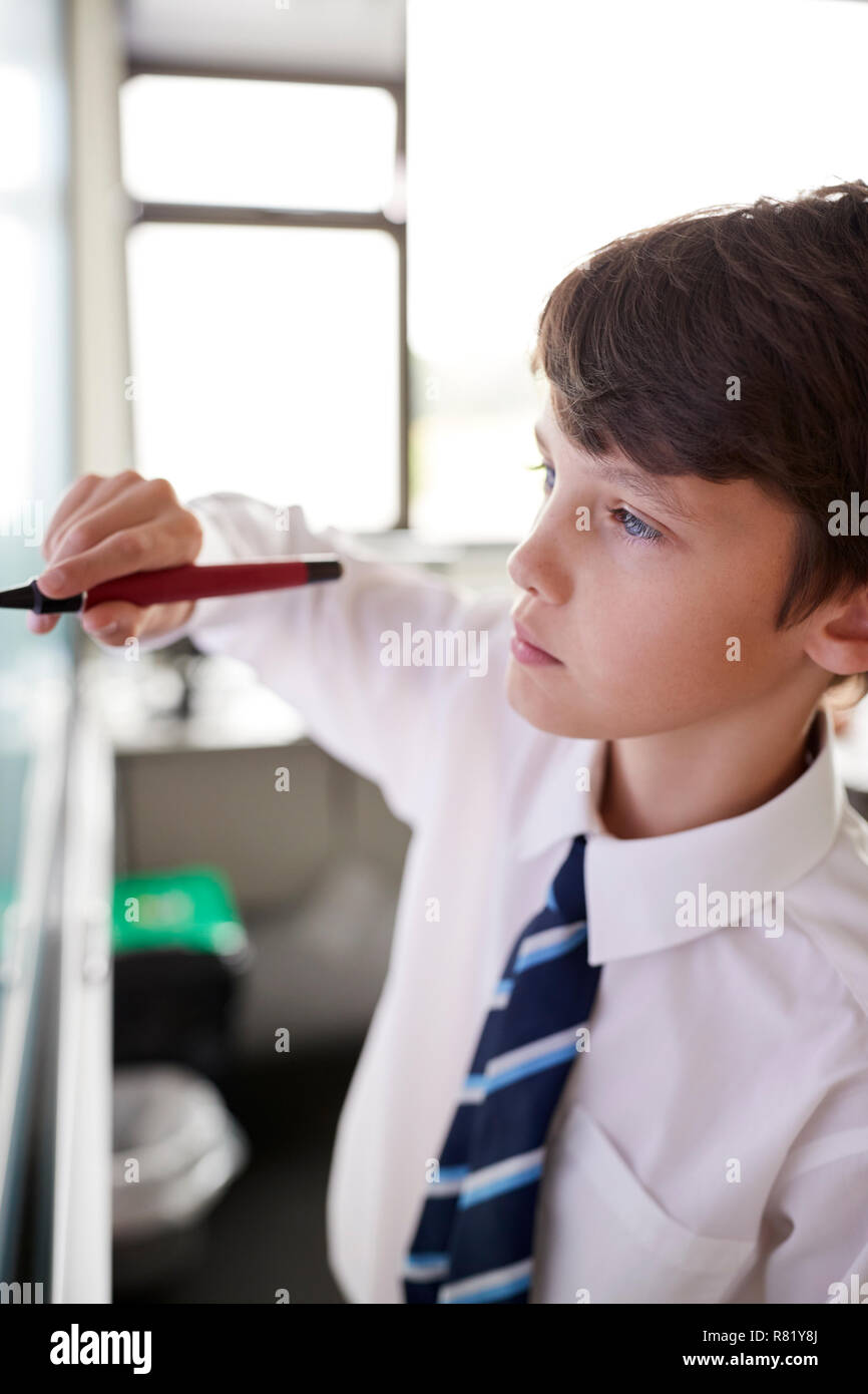 Homme Lycéen en uniforme à l'aide d'un tableau blanc interactif pendant la leçon Banque D'Images