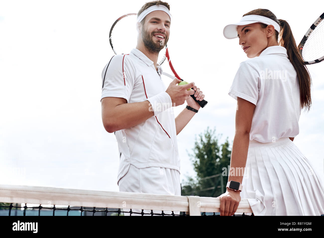Ils jouent comme une équipe. Belle jeune femme et l'homme holding tennis racket et discuter ensemble Banque D'Images