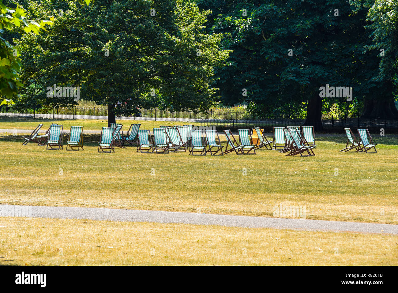 Transats vides à St James's Park, Londres, Royaume-Uni. Journée ensoleillée en été avec de l'herbe brune. Aucun client pour les sièges payants Banque D'Images