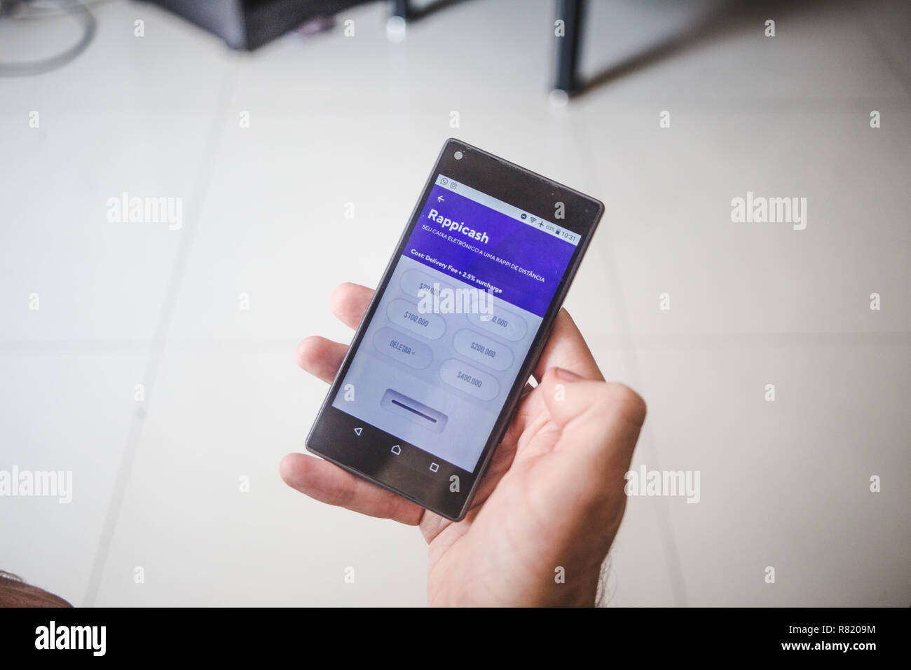 La main des hommes est titulaire du téléphone cellulaire à l'aide de l'app livraison colombienne, Rappi de rendre une ordonnance de paiement à Medellín, Colombie Banque D'Images