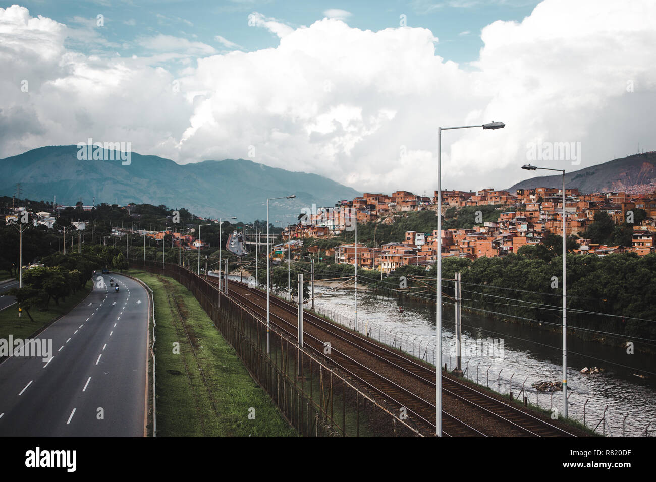 L'Autoroute, Rivière et chemin de fer dans la luxuriante ville vallonnée de Medellín, Colombie, avec la red maisons de barrios construit dans les collines Banque D'Images