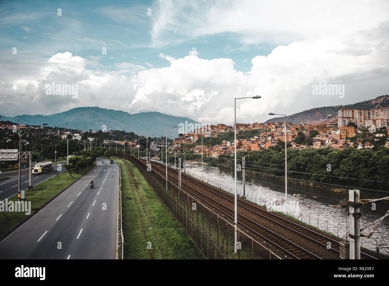 L'Autoroute, Rivière et chemin de fer dans la luxuriante ville vallonnée de Medellín, Colombie, avec la red maisons de barrios construit dans les collines Banque D'Images