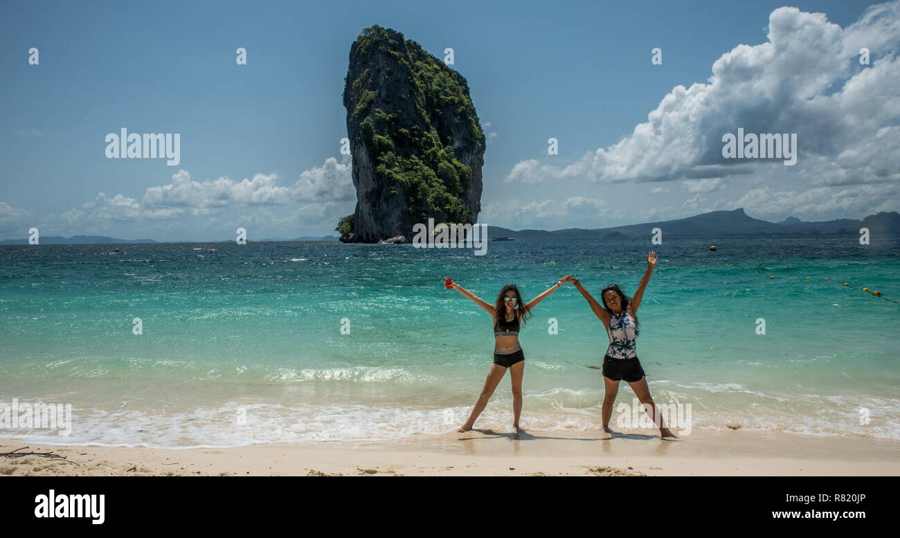 Mère et fille dansant sur une plage tropicale avec island dans l'arrière-plan Banque D'Images