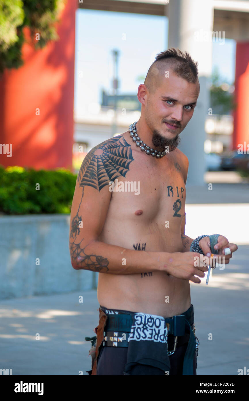 Un jeune homme pose pour photographe exhibant ses tatouages. Banque D'Images