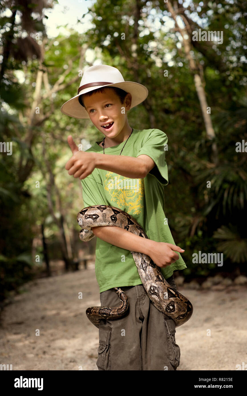 Cheerful Young boy posant avec un serpent enroulé autour de son corps. Banque D'Images