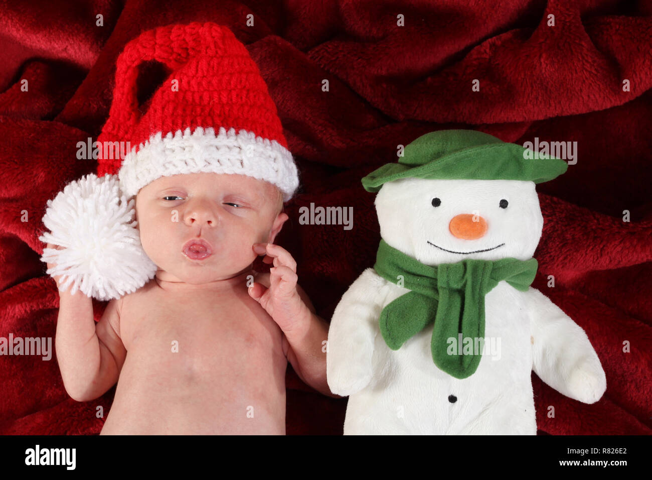 2 semaine baby boy dressed as Santa avec un bonhomme de neige Banque D'Images