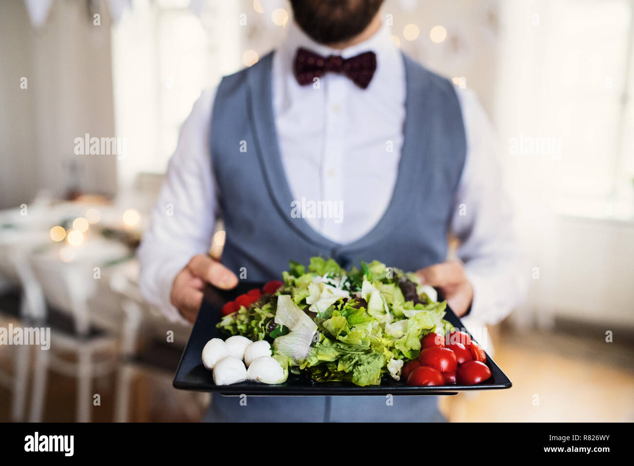 Portrait homme debout à l'intérieur dans un prix fixé pour une partie, tenant un plateau avec des légumes. Banque D'Images