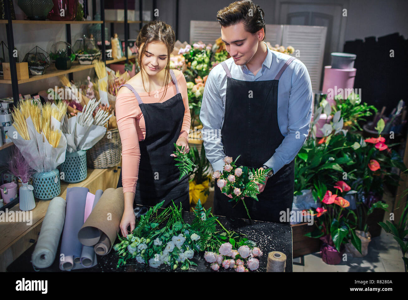 Jeunes hommes et des fleuristes, la création de bouquets et regarder les uns les autres. Ils sourient. Dans boueut Guy Tenir les mains. Banque D'Images