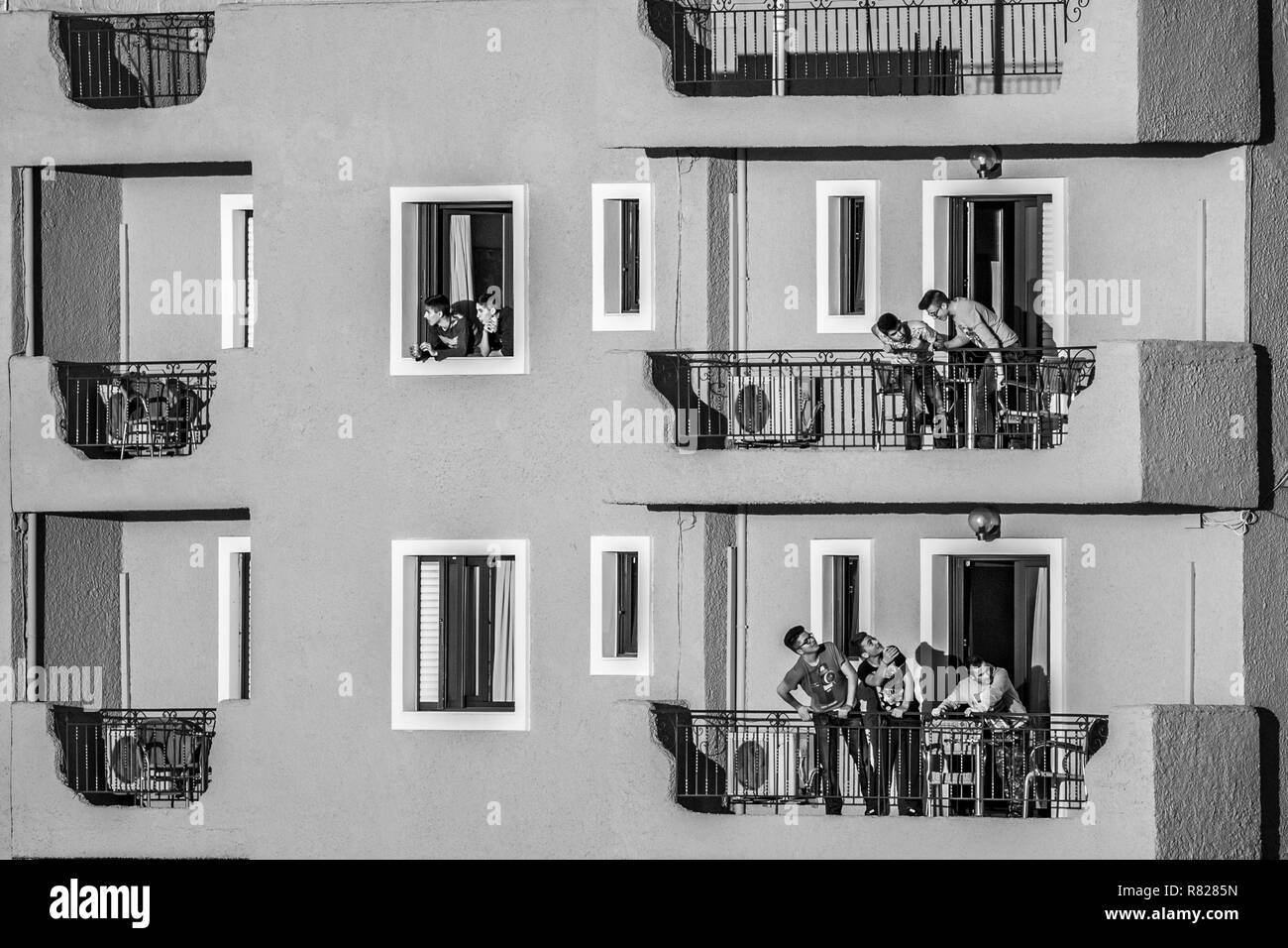IGOUMENITSA, GRÈCE - mars 2, 2017 : Groupe de jeunes hommes se parlent depuis les balcons et fenêtres d'un hôtel sur la promenade de la ville, Banque D'Images