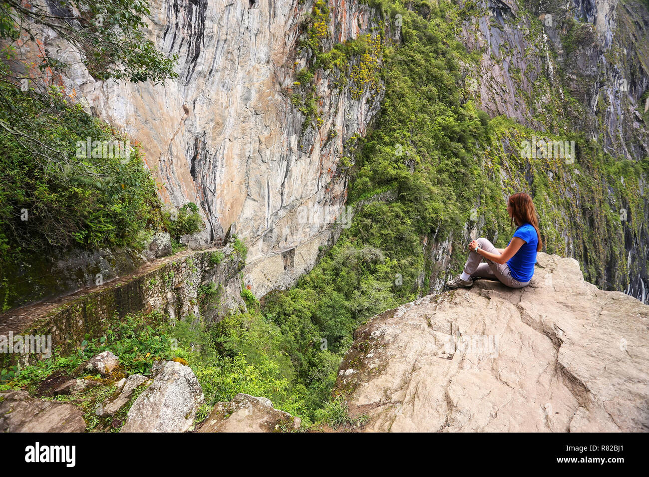Jeune femme en profitant de la vue du pont de l'Inca et Machu Picchu chemin près de falaise au Pérou. Le pont est une partie d'un sentier de montagne qui se dirige vers l'ouest à partir de la M Banque D'Images