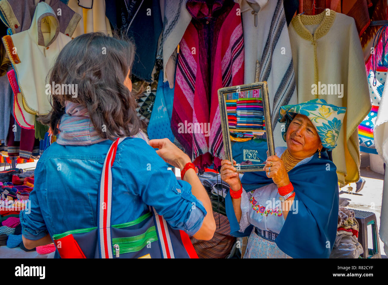 OTAVALO, ÉQUATEUR, 06 novembre 2018 : Close up of Hispanic woman holding autochtones un miroir pour les clients prouver leurs vêtements dans un marché de rue dans la région de Otavalo Banque D'Images