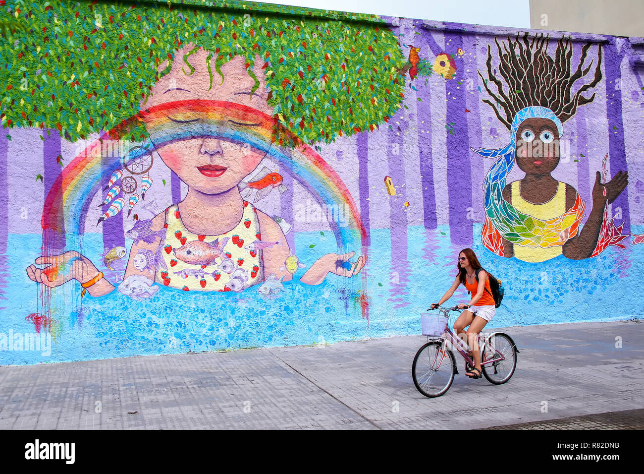 Jeune femme cycliste le long mur coloré à Montevideo, Uruguay. Montevideo est la capitale et la plus grande ville de l'Uruguay. Banque D'Images