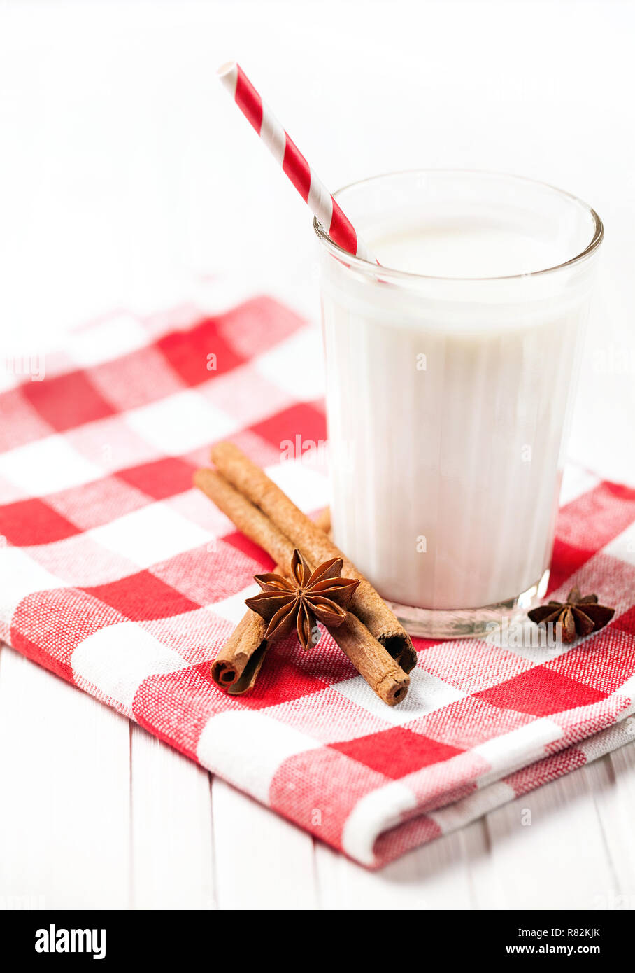 Lait avec la cannelle et anis en verre avec stick à rayures sur une table en bois blanc Banque D'Images