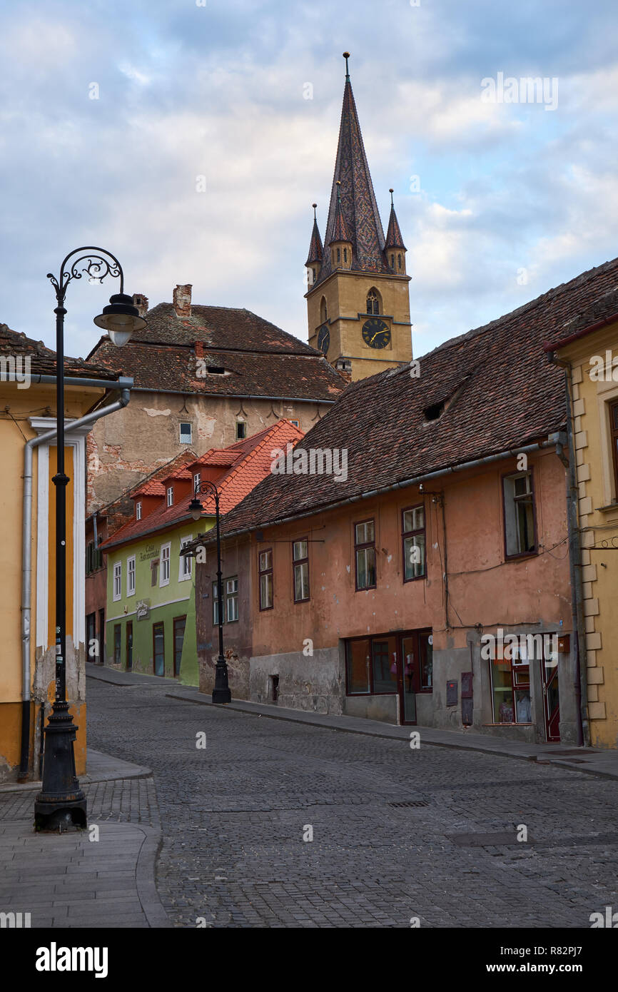 Pavés de rue typique ville de Sibiu en Roumanie, aux maisons colorées, clocher de l'église et lampadaire Banque D'Images