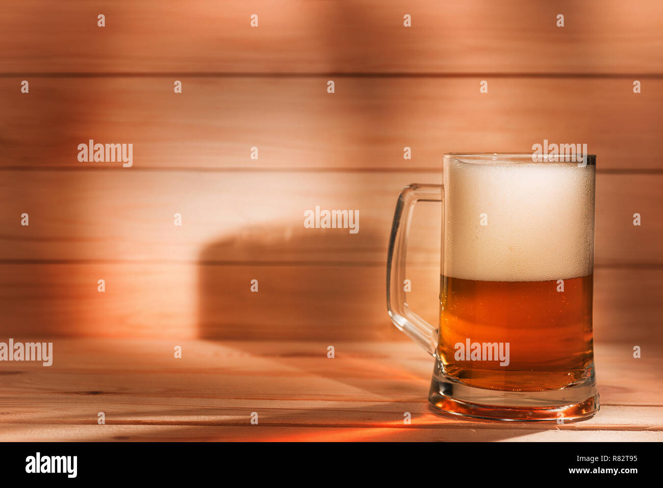 Pinte de bière sur fond de bois avec l'exemplaire de l'espace. Image couleur ambre Banque D'Images