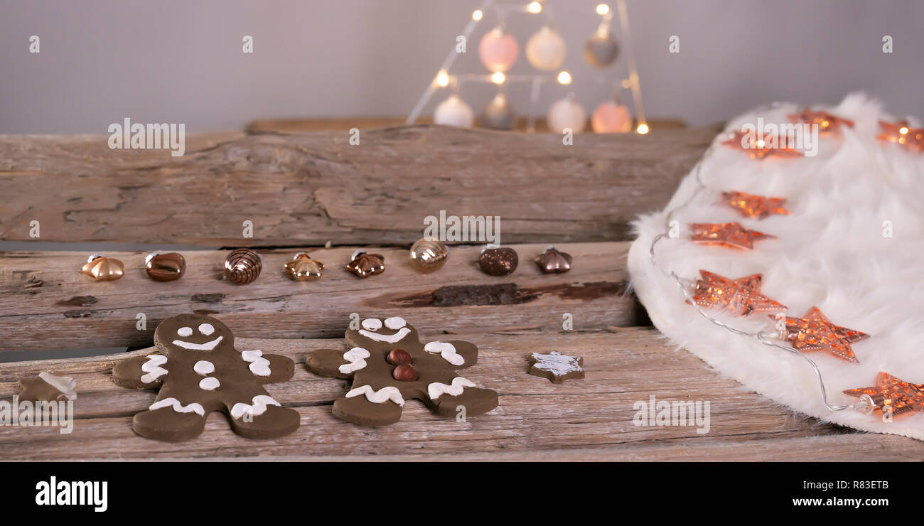 Gingerbread men couche avec couleur bronze pendentifs d'arbre de Noël sur un cuir blanc. La robe est sur de vieilles poutres en bois. Or Rosé fairy lights avec st Banque D'Images