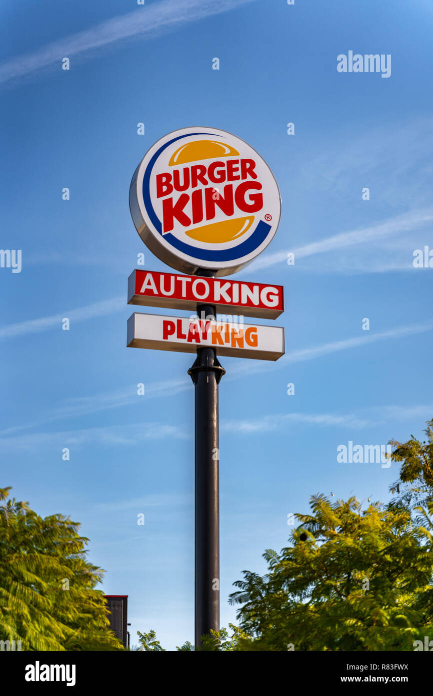Valencia, Espagne- 12 décembre 2018 : un grand arrondi Burger King, le roi de l'automobile et Playking signer contre le ciel bleu. Big Black post. Vert des arbres des deux côtés Banque D'Images
