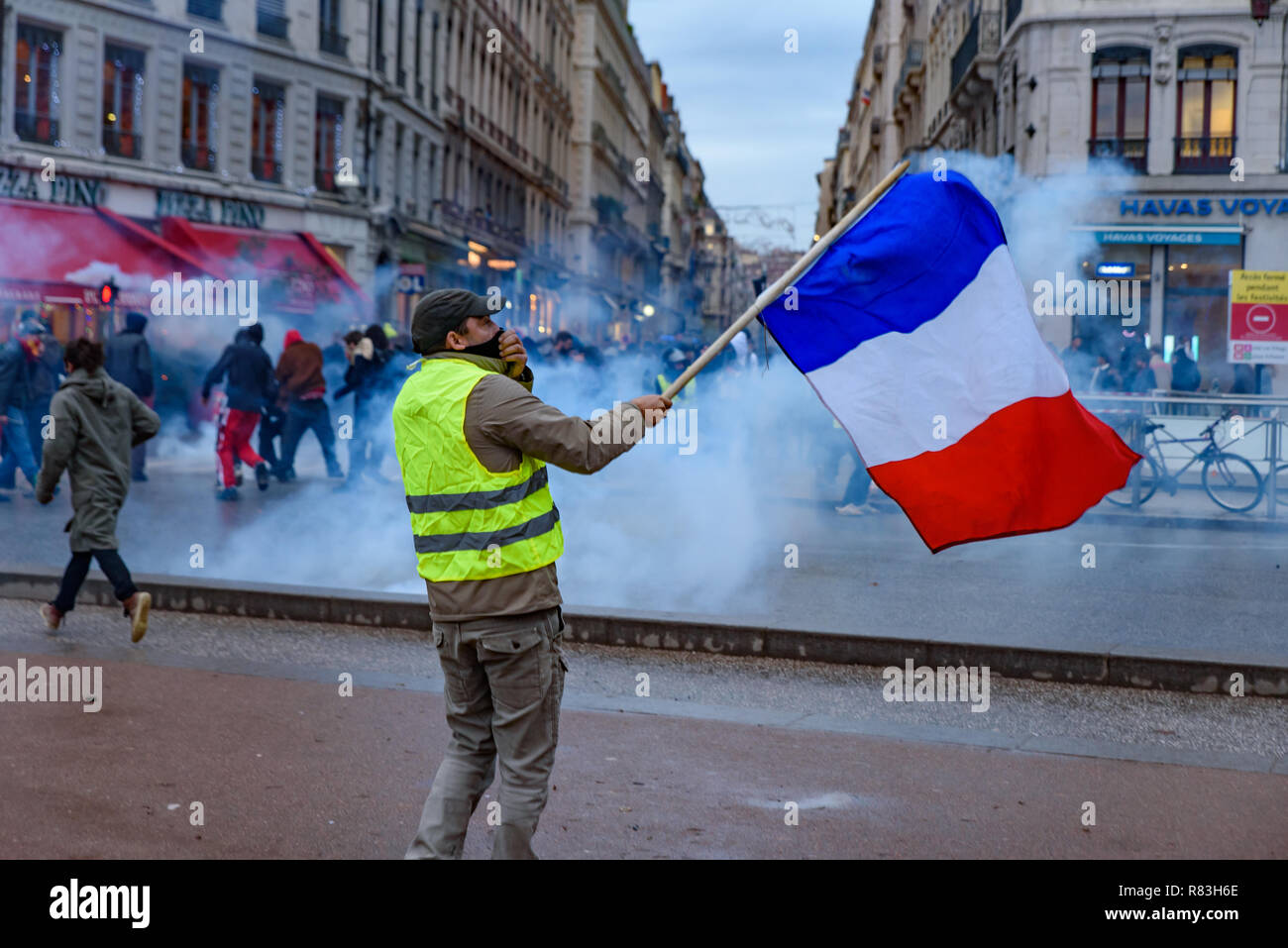 Jaune (gilets jaunes), protester contre la taxe sur les carburants, le gouvernement, et le président français Macron. Un manifestant a été en agitant le drapeau français à Lyon, France Banque D'Images