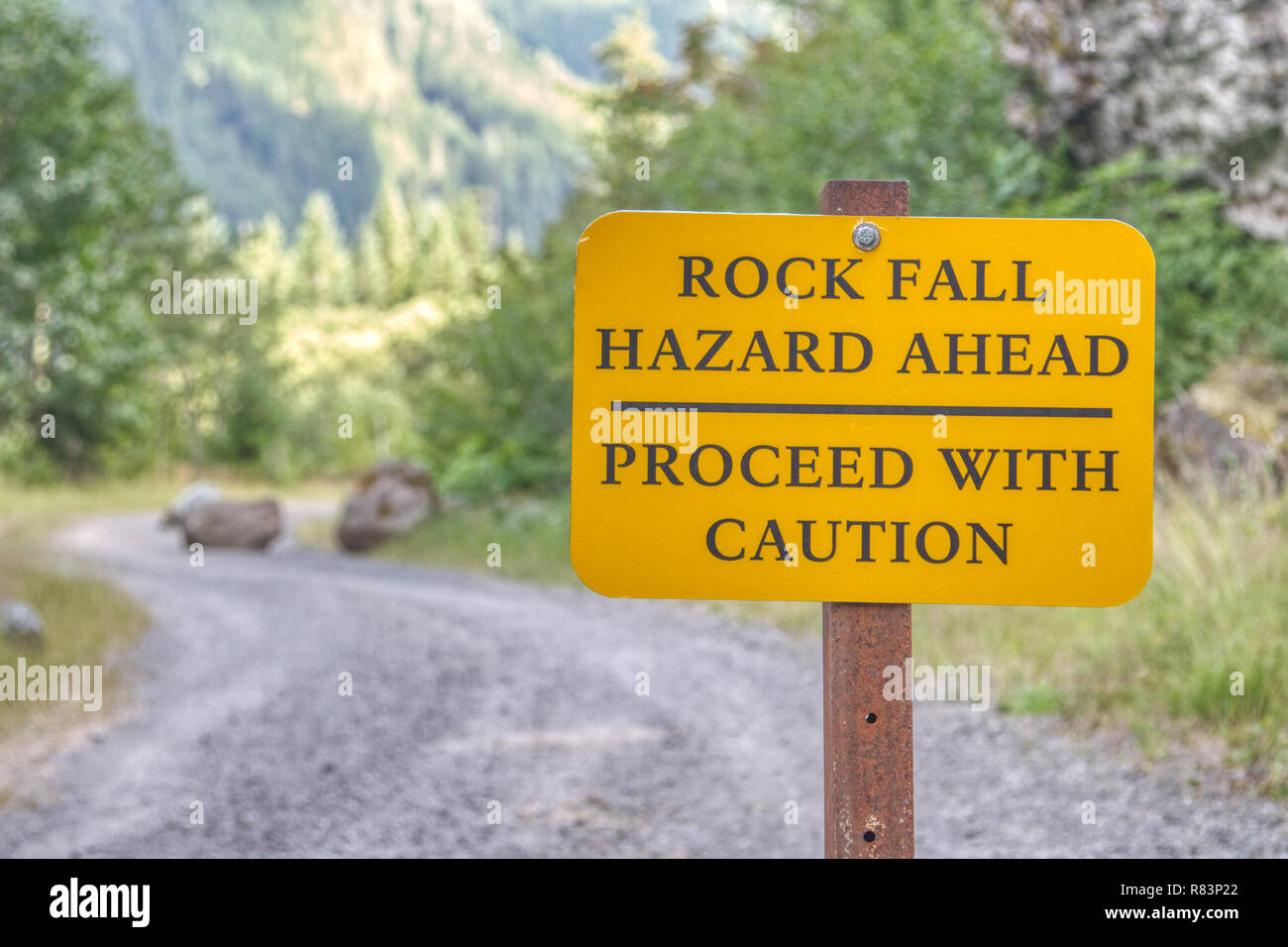 Ce panneau en Mt. Rainier National Park met en garde les randonneurs qu'ils entrent dans une zone dangereuse. D'énormes blocs tombés, jonchent la route dans l'arrière-plan. Banque D'Images