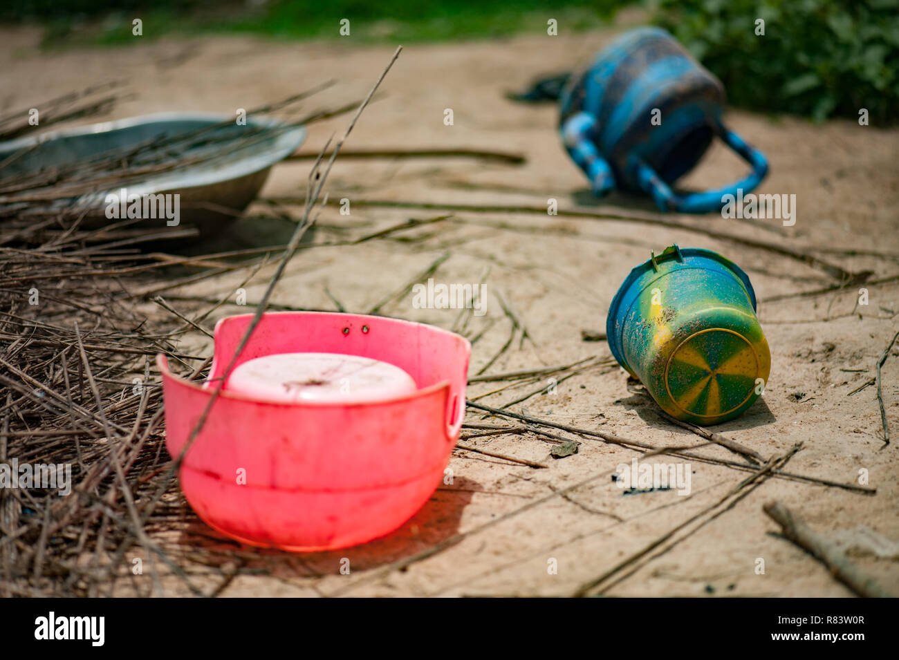 Le Mali, l'Afrique. Les pots en plastique met sur le sol sale dans un village près de Bamako Banque D'Images