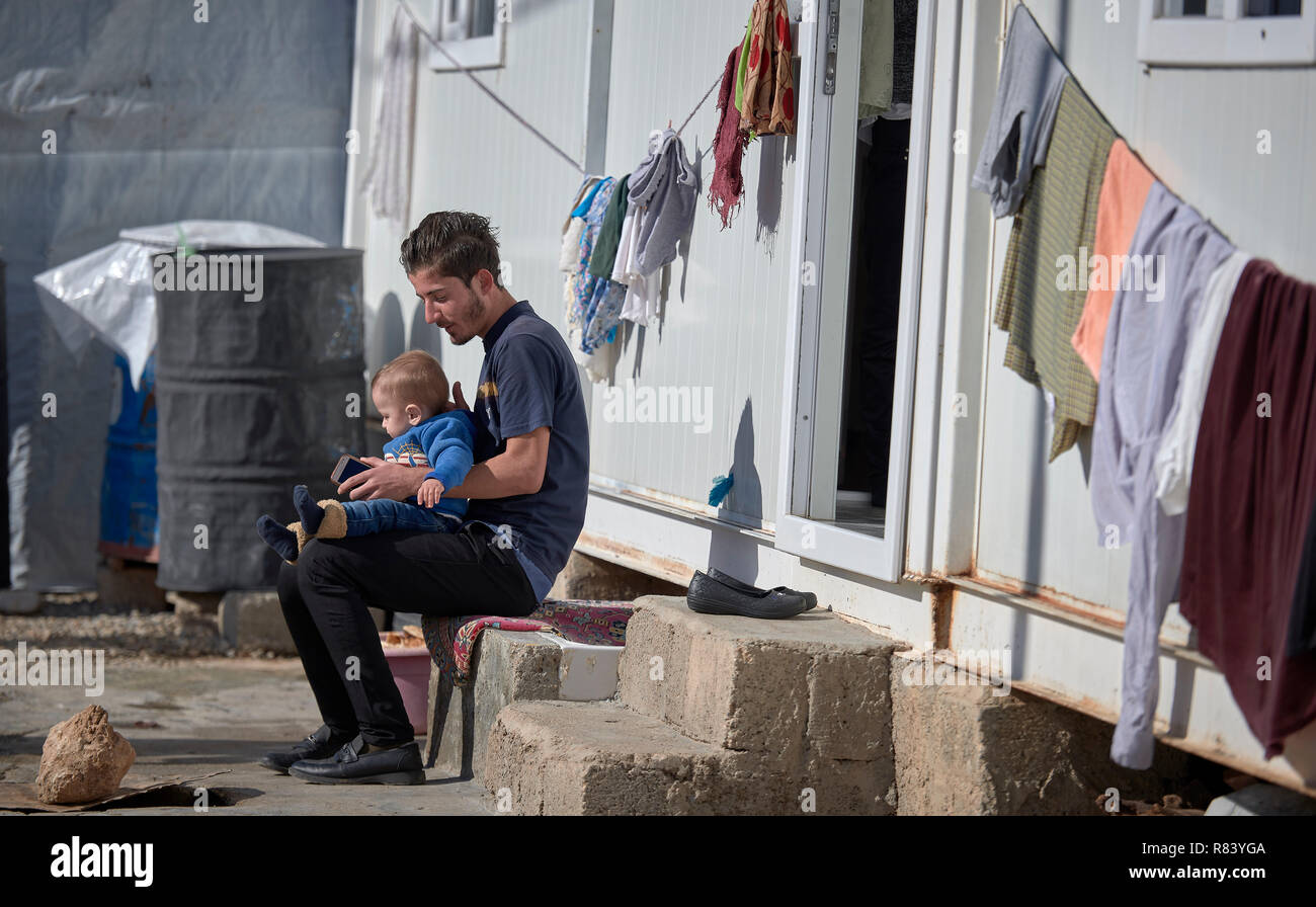 Yazidis, un homme est assis avec son enfant dans un camp de déplacés à Dawodiya dans le région du Kurdistan. Banque D'Images