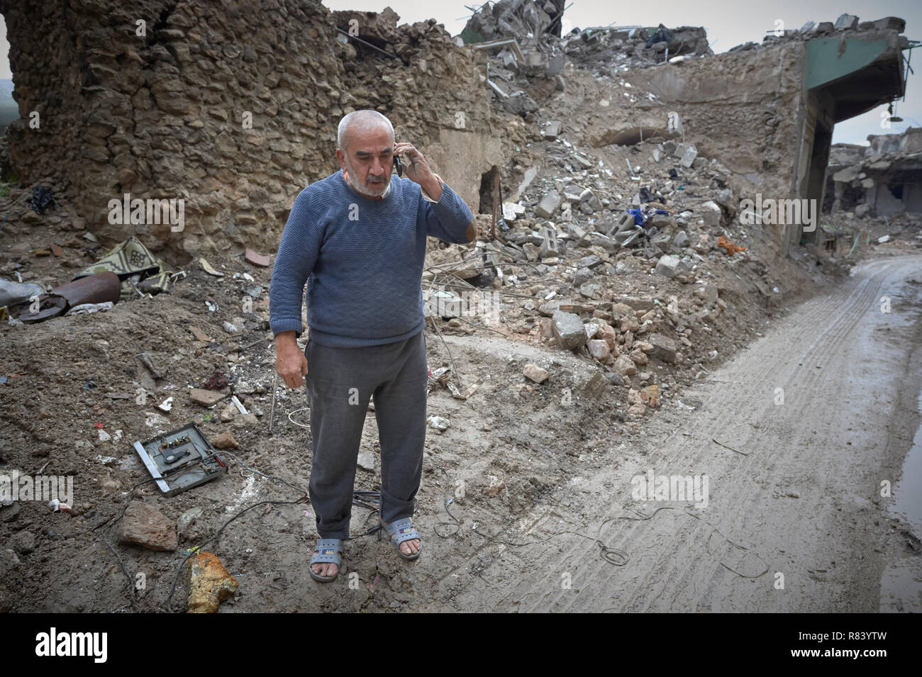 Un homme parle sur son téléphone mobile au milieu des décombres de la vieille ville de Mossoul, en Irak, qui a été dévastée au cours de la bataille de 2017 à Mossoul. Banque D'Images