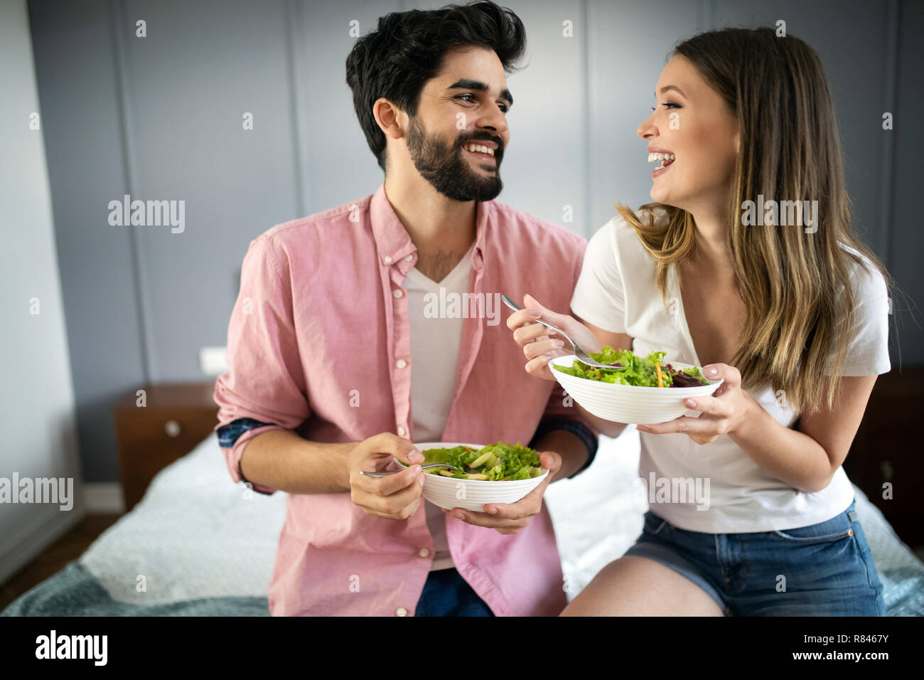 Belle jeune playful couple eating salad ensemble à la maison Banque D'Images