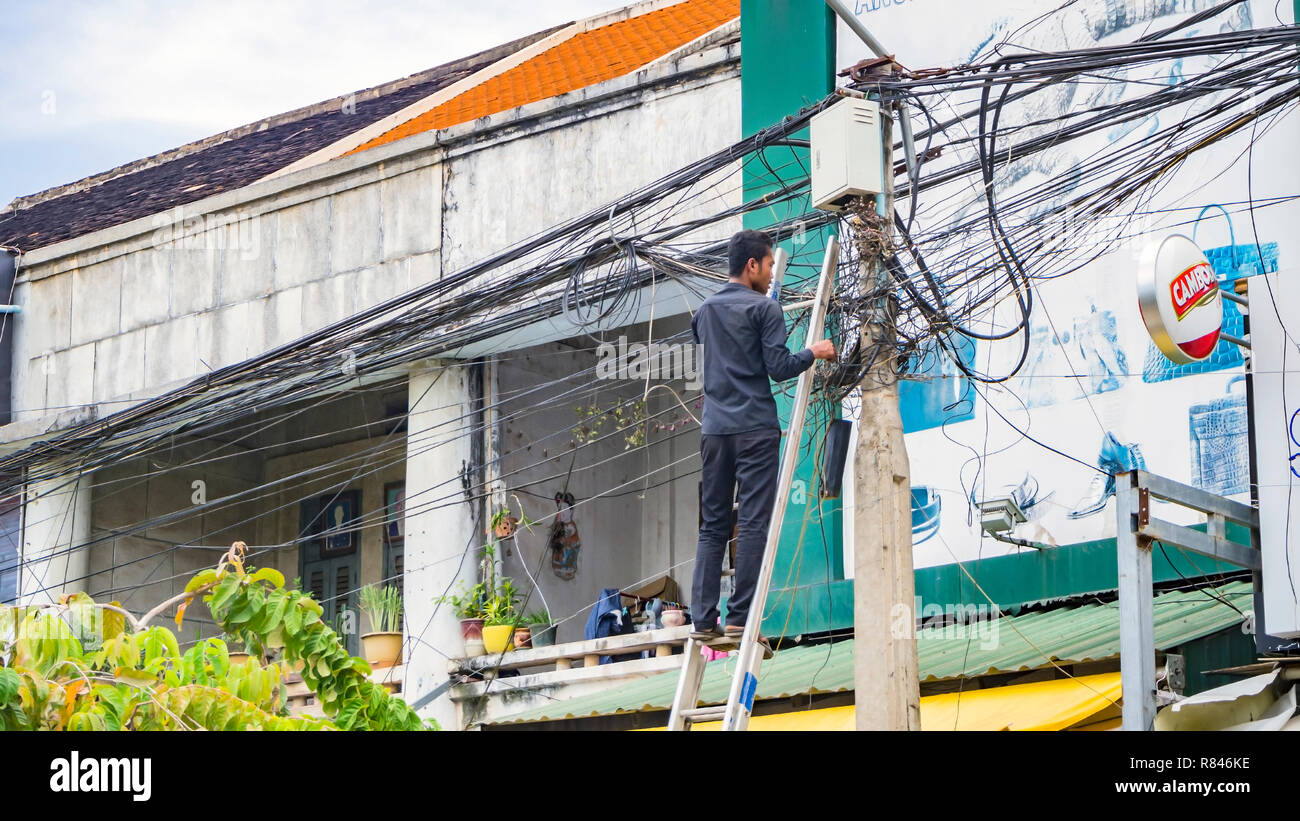 SIEM REAP, Cambodge - Novembre 13, 2017 : comité permanent sur l'échelle et de travail, la réparation de système de fil électrique Banque D'Images