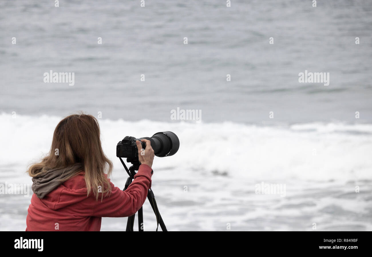 Femme photographe utilisant téléobjectif à la compétition de surf Banque D'Images