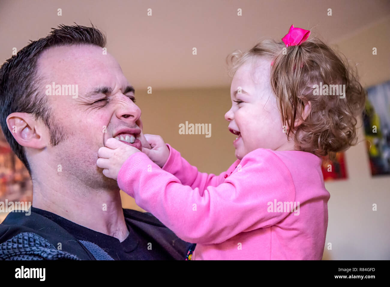 Un an, fille, s'amusant en pinçant les joues de son père. (MR) Banque D'Images