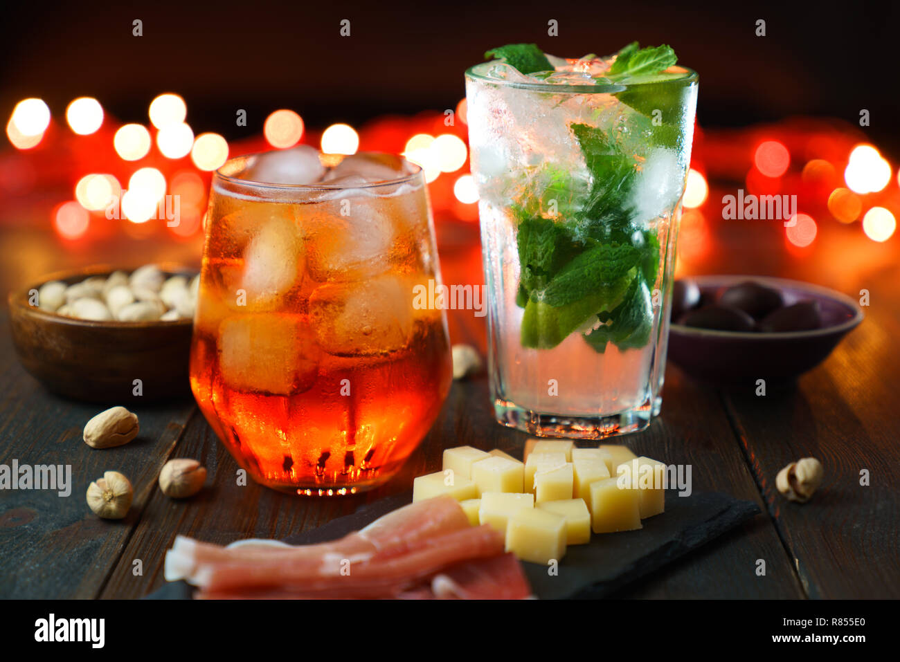 Happy hour avec aperol spritz, mojito, jambon, olives, pistaches et fromage. Lumières de fête en haute résolution, l'effet bokeh Banque D'Images
