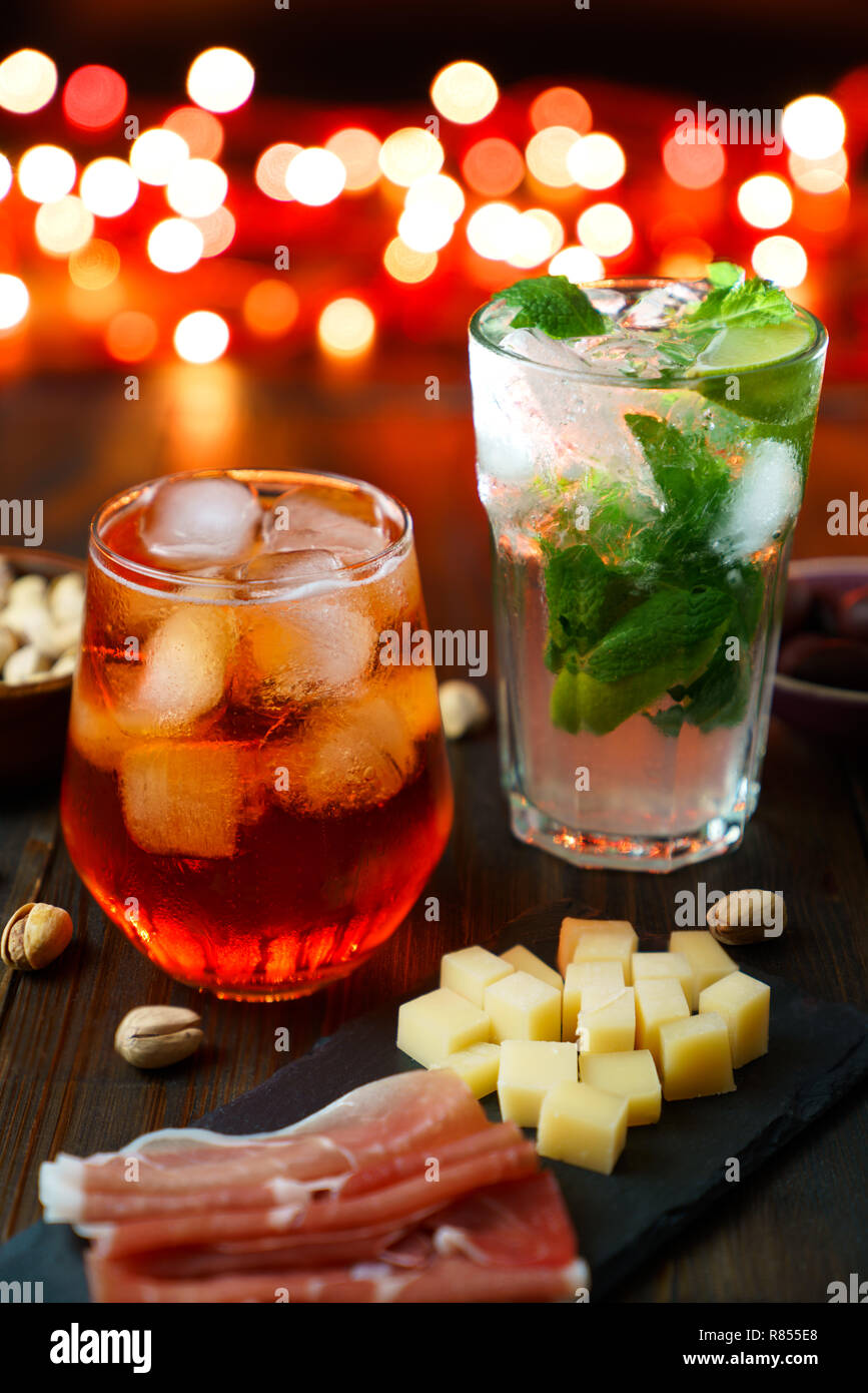 Happy hour avec aperol spritz, mojito, jambon, olives, pistaches et fromage. Lumières de fête en haute résolution, l'effet bokeh Banque D'Images
