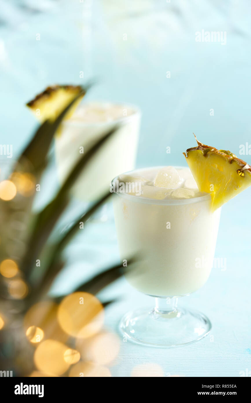 Pina Colada servi avec des tranches d'ananas. Les feuilles d'ananas avec lumières de fête en effet bokeh, fond bleu, une haute résolution Banque D'Images